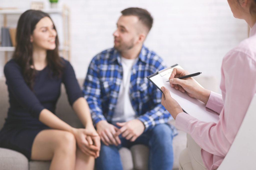 Falling in love again. Young cheerful couple at consultation with personal psychologist, free space